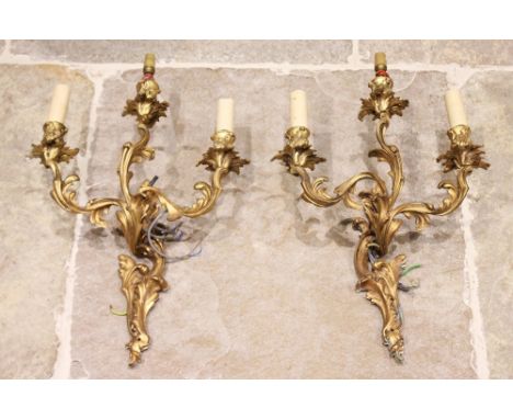 A pair of French rococo style ormolu three-branch wall sconces, early 20th century, each cast as scrolling intertwined foliag