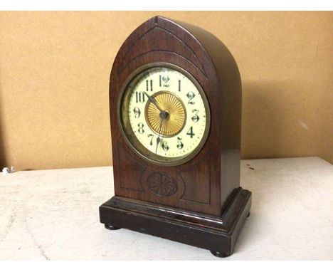 An early 20thc mahogany mantle clock with pointed top with enamel and gilt metal dial, on plinth base supported by bun feet (