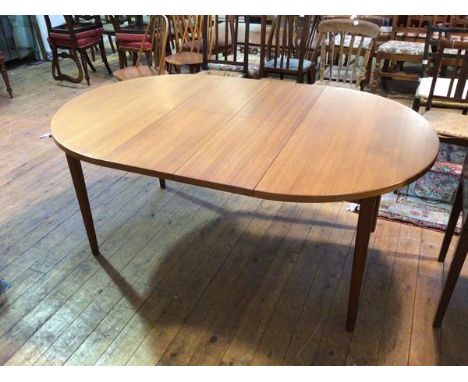 A mid century style circular teak extending dining table, with two leaves stored below top, on turned supports (open: 72cm x 