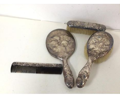 An Edwardian London silver dressing table set with hand mirror (28cm), hair brush, clothes brush and comb, all with cherubic 