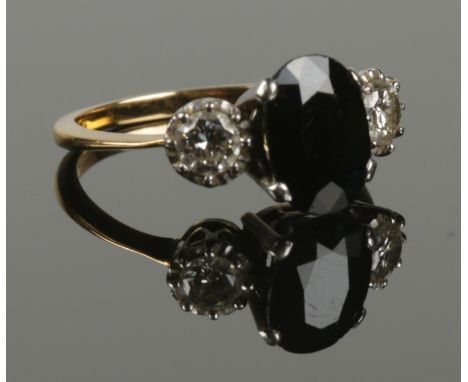 An 18ct gold sapphire and diamond ring. The sapphire flanked by a pair of diamonds. 3.19g. Size J 1/2.  