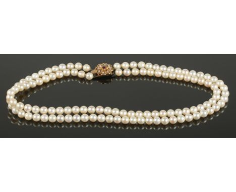 A two row string of cultured pearls with 9ct gold seed pearl and ruby floriform clasp. length 20cm  