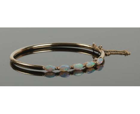 A 9ct gold bangle set with five opal stones.  