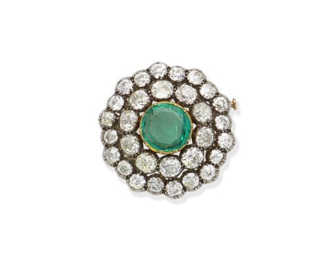 An emerald and diamond broochThe circular-cut emerald within a tiered surround of old brilliant and cushion-shaped diamonds, 