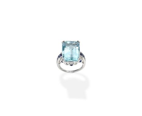 An aquamarine, sapphire and diamond dress ringThe step-cut aquamarine between shoulders of calibré-cut sapphires, accented by