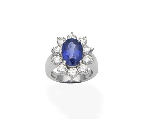 A sapphire and diamond cluster ringThe oval-cut sapphire within a brilliant-cut diamond surround, mounted in 18 carat white g