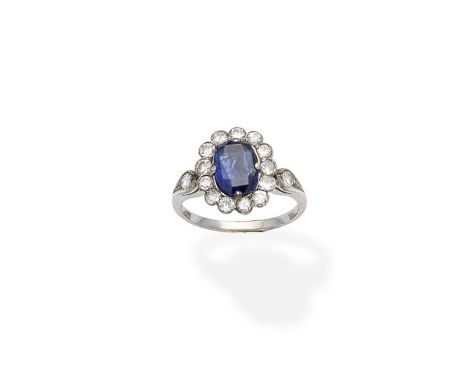 A sapphire and diamond cluster ringThe cushion-shaped sapphire within a surround of brilliant-cut diamonds, between tapering 