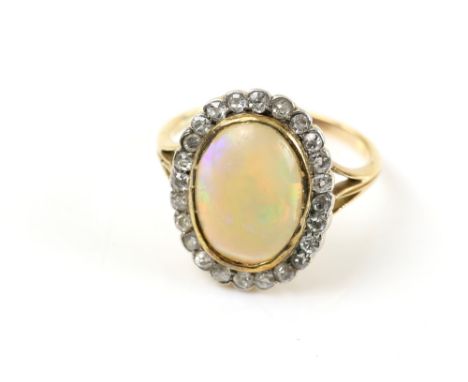 Early 20th C opal and diamond cluster ring, oval cabochon cut opal, measuring 12 x 9mm, set in a frame of old cut diamonds, m