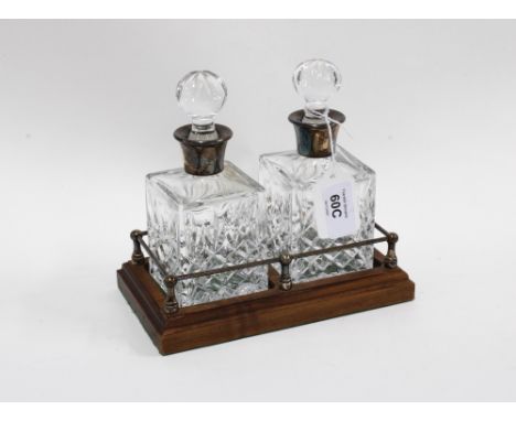 A pair of small glass decanters with stoppers and silver collars, with  a wooden stand, Birmingham 1987