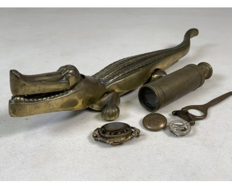 A collection of brassware, mourning brooch, spy glass, badges and a large brass crocodile nut cracker. W:34cm