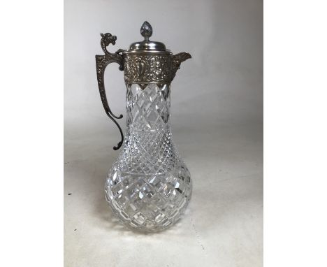 An unmarked white metal mounted  cut glass claret jug with dragon head handle, acorn finial and figural head spout. H:30cm