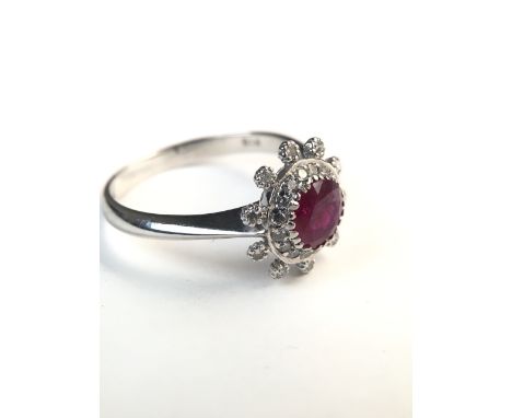 An 18ct white gold ruby and diamond flower ring. central round free cut ruby with a surround of single cut diamonds. 2.8g. Si