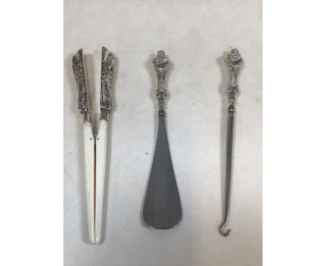 Three silver handled items including a button hook, a shoe horn and a glove stretcher 