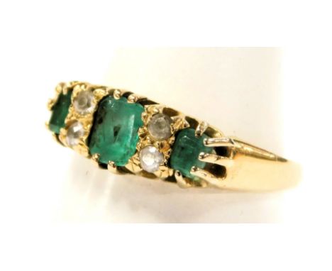 An 18ct gold and emerald three stone ring, interspersed with two pairs of diamonds at intervals, in a claw setting, size M, 2