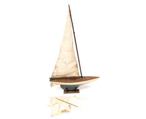 An early 20thC wooden scale model pond yacht, with rigging and sales, raised on a wooden stand, 91cm long.