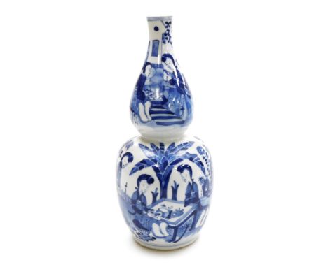 A Qing dynasty blue and white porcelain double gourd vase, decorated with women seated in a garden setting, Kangxi four chara