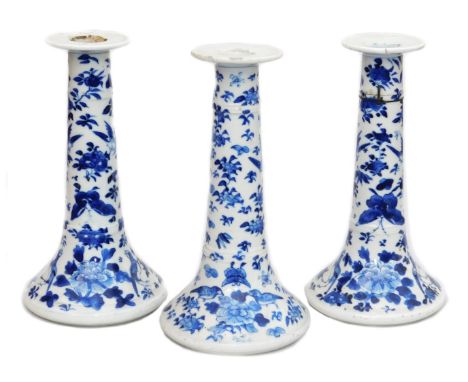 A pair of Qing dynasty blue and white porcelain candlesticks, of outswept form, decorated with birds, butterflies and flowers