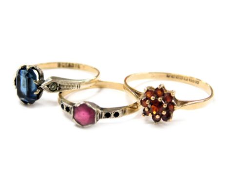 A 9ct gold and garnet set flowerhead ring, size S, 1.4g, together with two 9ct gold, silver and gem set rings, 3.1g.  (3)