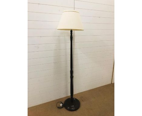 A floor standing lamp on an oak turned base with cream shade