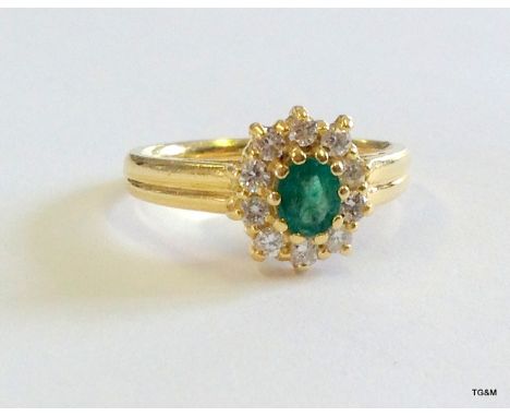 An 18ct gold diamond and emerald cluster ring size K/L