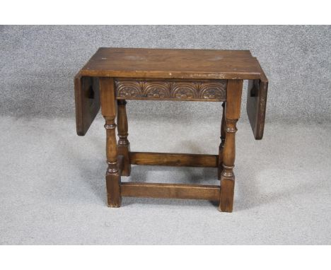 A small mid century oak Jacobean style twin drop flap occasional table with carved frieze on turned stretchered supports. H. 