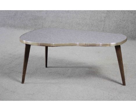 A mid century shaped coffee table with composite laminated top on splay supports. H.34 W.76 D.43 