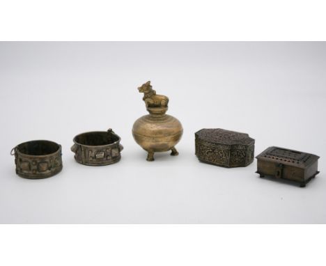 A pair of studded white metal cuffs along with two pierced design trinket boxes and a brass censer with a cow finial. 5 piece