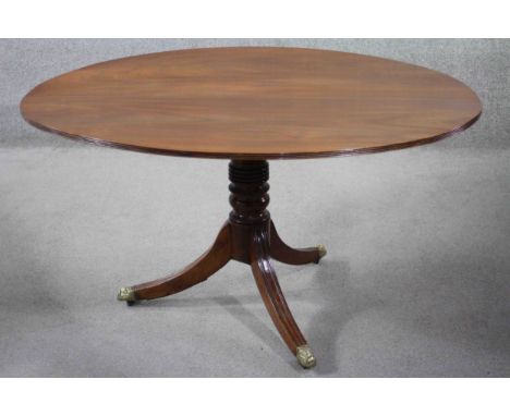 A Regency figured mahogany tilt top dining table on turned central column on swept reeded tripod supports. H.70 W.132 D.106 c