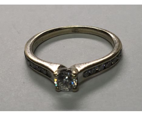 An 18carat gold ring set with a brilliant cut solitaire diamond the shank set with further diamonds, ring size L.