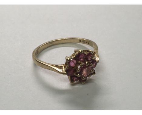A 9carat gold ring set with a pattern of ruby coloured stones. Ring size L.