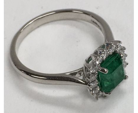 A platinum (950) cushion cut emerald and diamond set ring. (L.5).