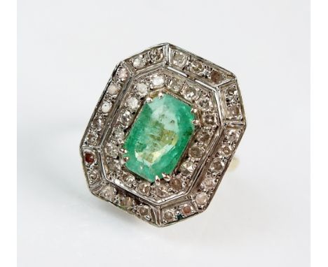 An Art Deco emerald and diamond octagonal cluster ring, designed as a central trap cut emerald claw set within two eight cut 