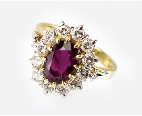 An 18ct gold ruby and diamond cluster ring, designed as a central oval mixed cut ruby claw set within a surround of twelve br