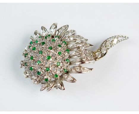 A diamond and emerald stylised sunflower bar brooch, designed as an emerald set 'seed' centre within a graduated surround of 