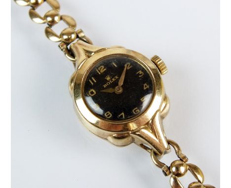 A lady's 9ct gold Rolex wristwatch, the circular black dial with gold Arabic numerals, manual wind, with attached 9ct gold ci
