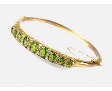 An Edwardian 9ct gold garnet topped doublet and diamond set hinged bangle, designed as nine oval mixed cut garnet topped doub