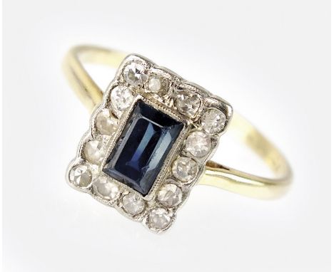 An Art Deco sapphire and diamond cluster ring, designed as a central raised rectangular cut sapphire collet set within a bord