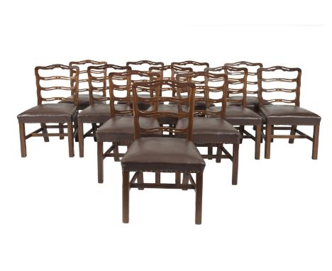 A SET OF TWELVE GEORGE IV STYLE MAHOGANY FRAMED DINING CHAIRS, with pierced undulating ladder backs, padded seats covered in 