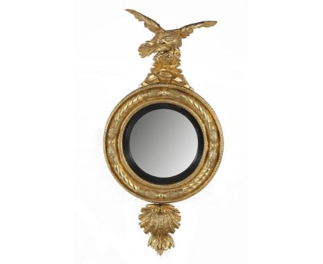 A REGENCY GILTWOOD CONVEX WALL MIRROR, the ropework frame surmounted with a crouching eagle on rockwork, the base decorated w