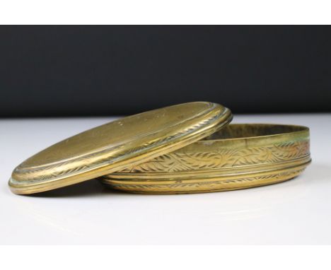 An antique 18th century oval brass snuff box with ornate chased decoration. 