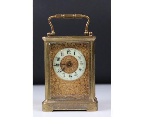 An antique brass cased carriage clock with bevelled glass panels and decorative face and dial, complete with key. 