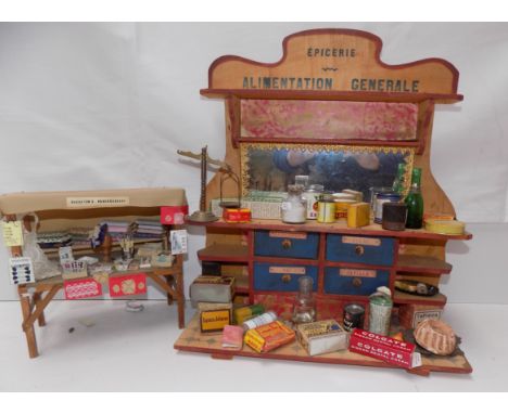 A French shop display shelf unit containing a quantity of grocery tins and packets, together with a haberdashery market stall