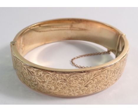 A 9 carat gold hinged bangle engraved foliage decoration, 19g