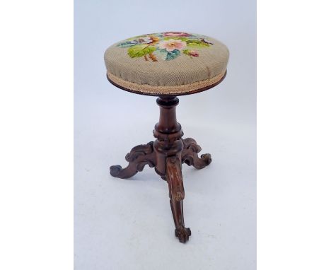 A Victorian revolving Rosewood piano stool with carved decoration and tapestry top 