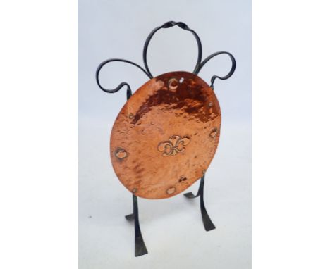 An Art Nouveau wrought iron and copper oval embossed firescreen with fleur de lys decoration 78cm tall