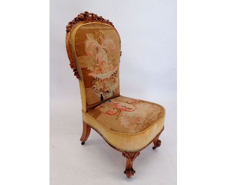 A Victorian nursing chair with finely carved scrollwork surmount and original petit point tapestry 