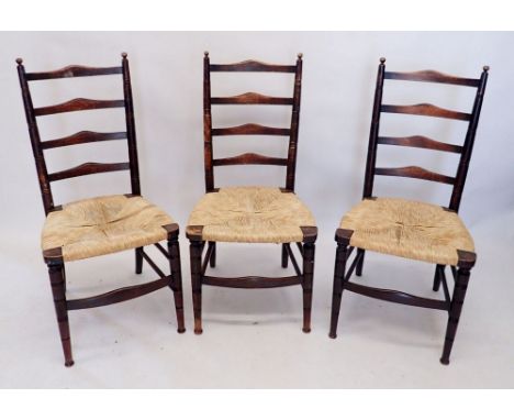 Three Arts and Crafts ladder back rush seated chairs by Urquhart and Adamson, Liverpool and believed to be retailed by Libert