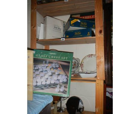 A shelf of games including glass chess set.