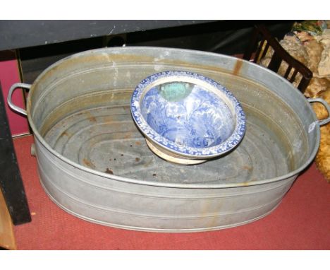 An old galvanised two handled bath, together with blue and white toilet basin