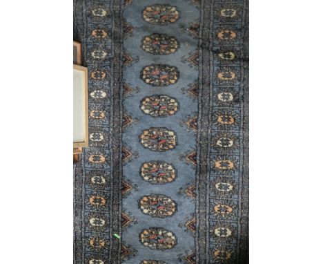 A WOOL RUNNER the light blue ground with central pelmets within a conforming border 187cm X 63cm